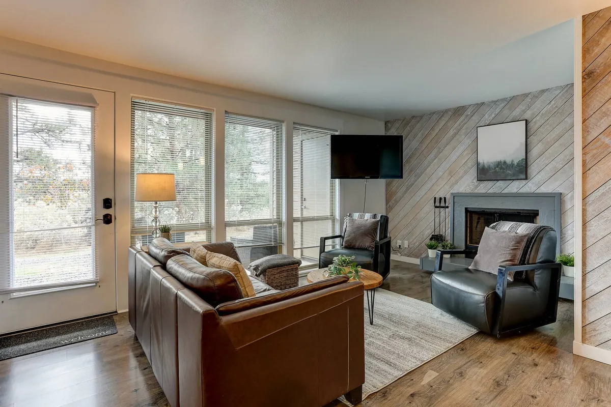 A comfortable living area with a leather sofa, armchairs, a fireplace, television, and large windows. The atmosphere is cozy and perfect for relaxing, watching movies, or spending time with loved ones.
