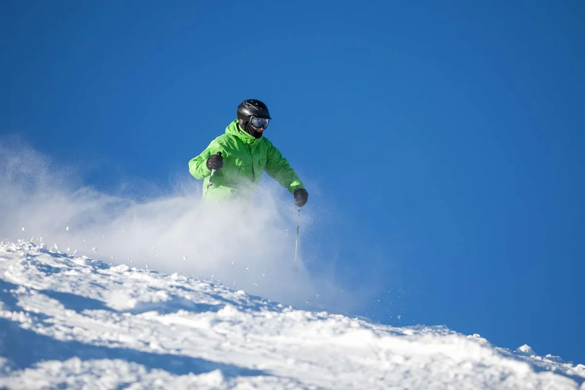 A skier navigates a snowy slope under a clear blue sky, capturing the thrill of winter sports available at the resort. The snow-covered landscape provides a vivid sense of seasonal adventure and family-friendly recreation during the colder months.